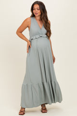 woman wearing a light green striped maternity maxi dress with a ruffled neckline and flared hem, showcasing her baby bump