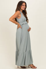 woman wearing a light green striped maternity maxi dress with ruffle details and holding her baby bump