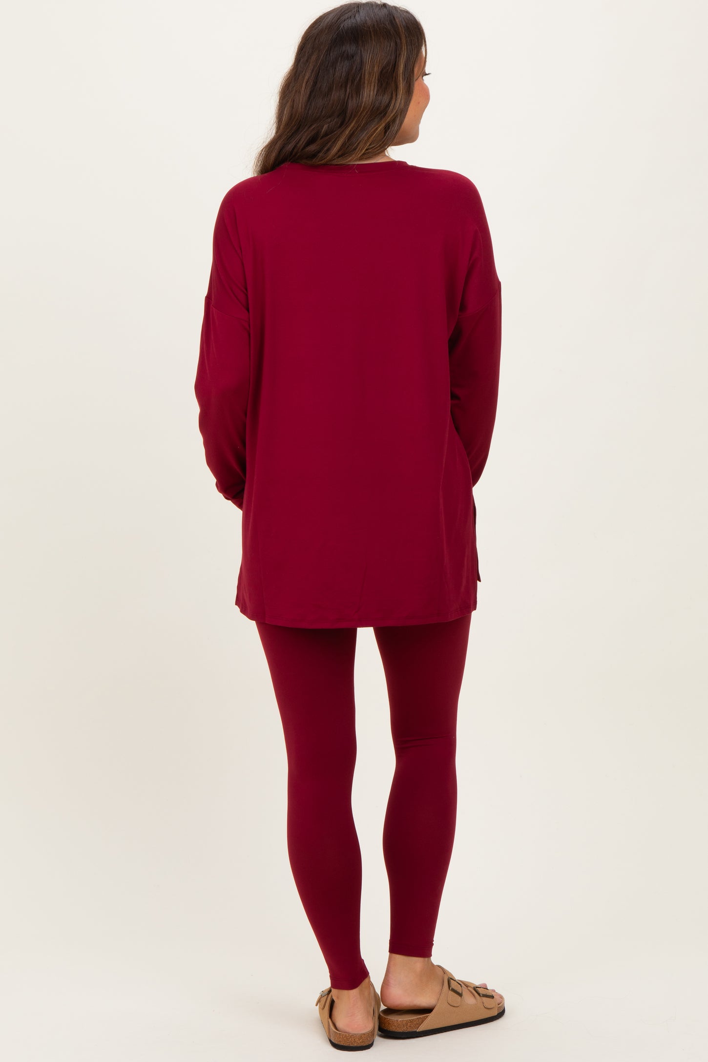 woman wearing a maroon long sleeve maternity tunic top and matching leggings, with a relaxed fit and back view displayed