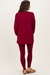 woman wearing a maroon long sleeve maternity tunic top and matching leggings, with a relaxed fit and back view displayed