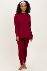 woman wearing a burgundy long sleeve top and matching leggings, standing with bare feet and a headband in her hair