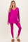 woman wearing a hot pink maternity top and matching leggings, with a visible baby bump, styled with cozy slippers