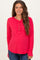 woman wearing a red long sleeve maternity top with button details and a visible baby bump