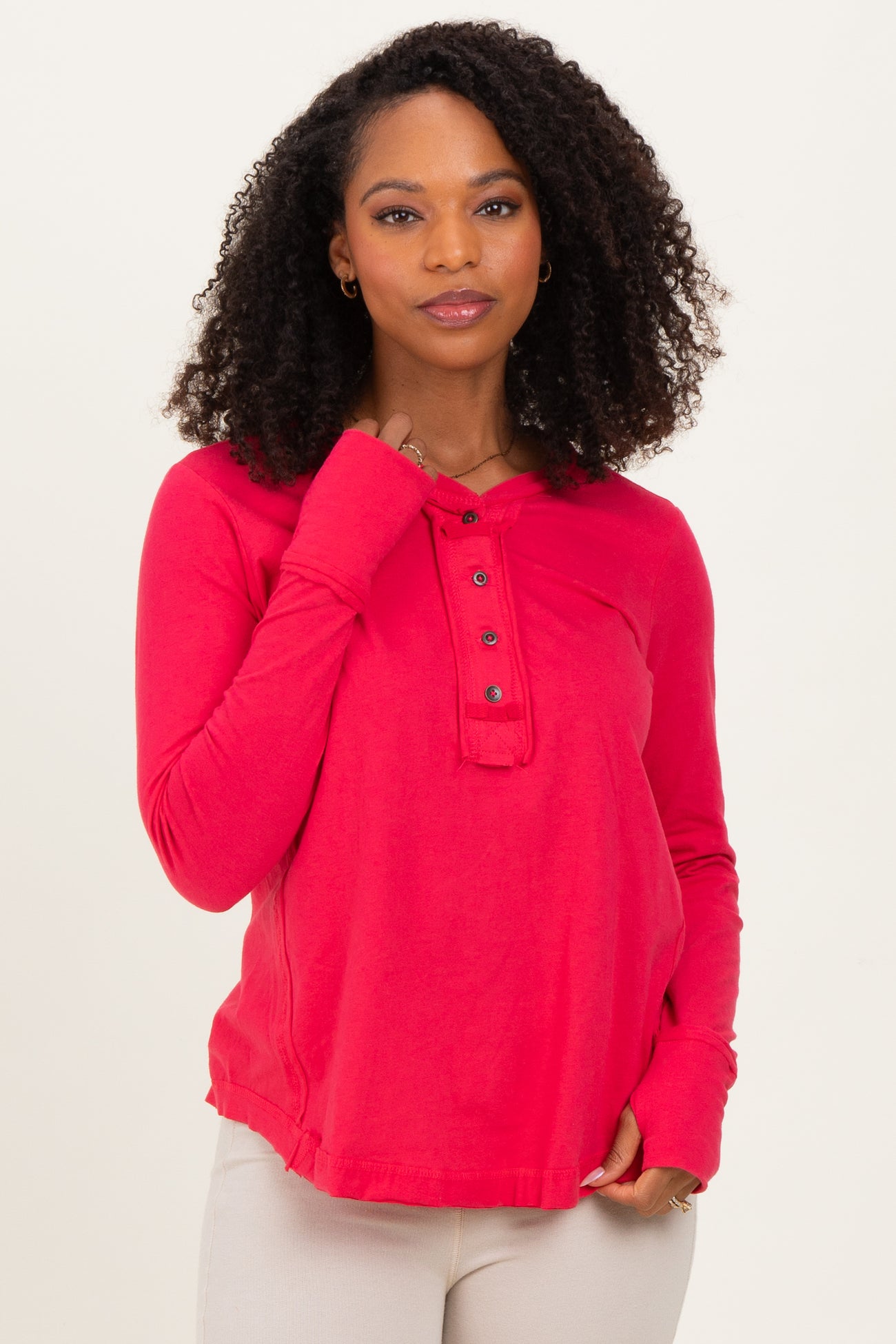 woman wearing a bright red long sleeve henley shirt with button details and a relaxed fit