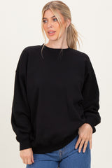 woman wearing a black oversized sweatshirt with a round neckline and long sleeves, styled with blue jeans