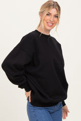 woman wearing a black oversized sweatshirt with long sleeves and a relaxed fit, paired with blue jeans