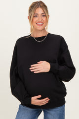 woman wearing a black oversized maternity sweatshirt and holding her baby bump