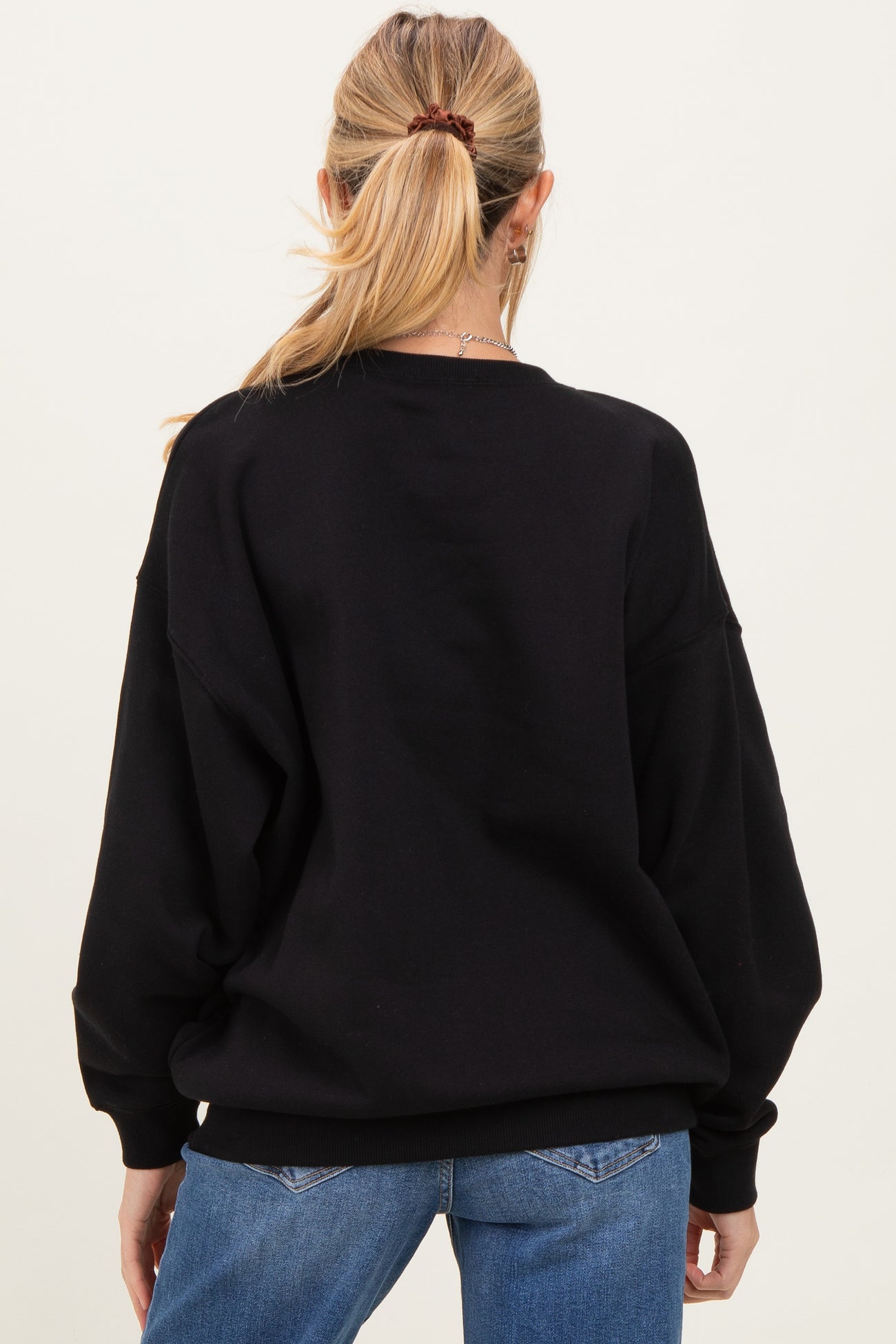 woman wearing a black oversized maternity sweatshirt with a relaxed fit, seen from the back