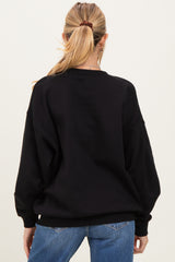 woman wearing a black oversized maternity sweatshirt with a relaxed fit, seen from the back