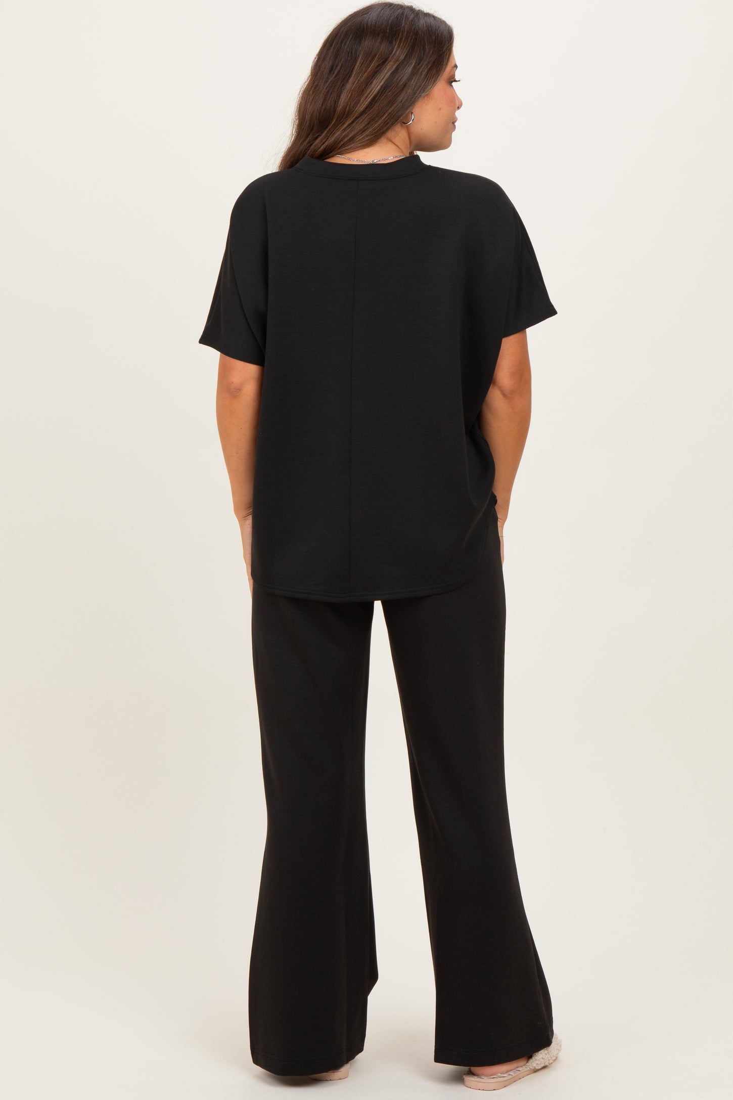woman wearing a black maternity top and matching flared maternity pants, view from the back