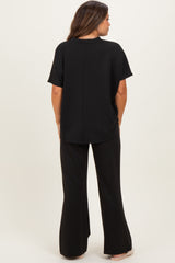 woman wearing a black maternity top and matching flared maternity pants, view from the back