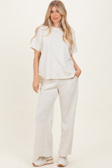 woman wearing a light gray oversized t-shirt and matching wide-leg sweatpants, posing with hands in pockets