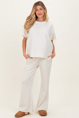 woman wearing a light gray maternity loungewear set with a relaxed fit top and wide-leg pants, showcasing a baby bump