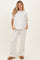 woman wearing a light gray maternity loungewear set with a relaxed fit top and wide-leg pants, showcasing a baby bump