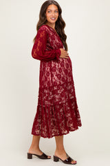 woman wearing a burgundy maternity lace dress with long sleeves and a baby bump visible