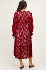 woman wearing a burgundy lace maternity dress with long sleeves and a tiered skirt, showing a flowy silhouette