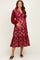 woman wearing a burgundy lace maternity dress with long sleeves and a tiered skirt, holding her baby bump