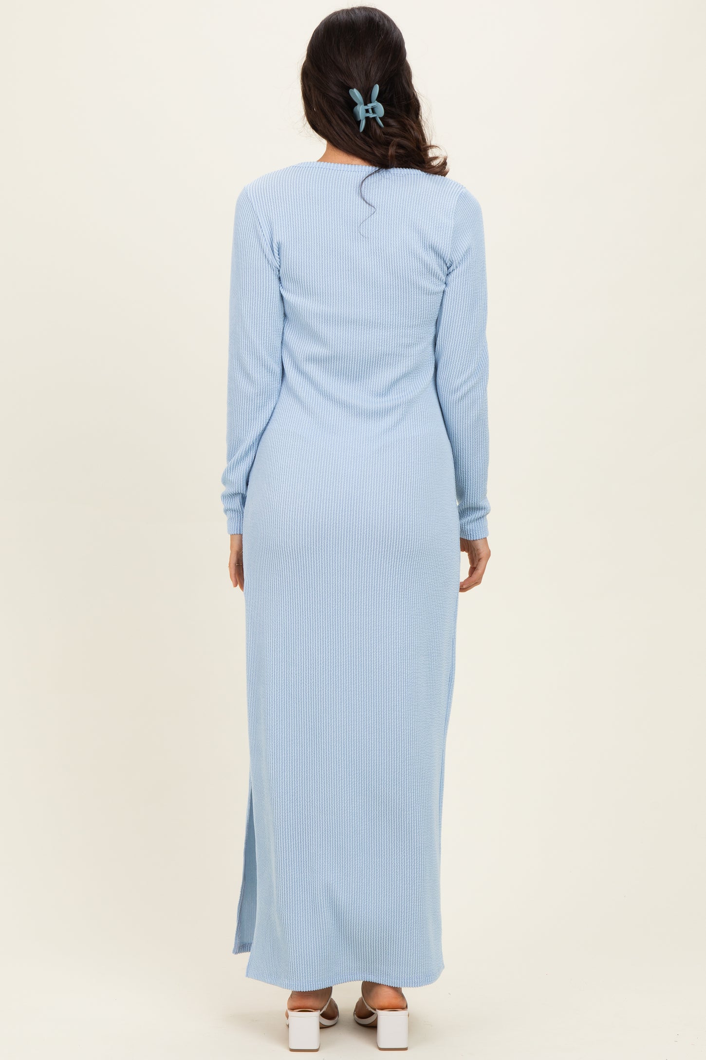 woman wearing a light blue ribbed maxi dress with long sleeves and side slits, viewed from the back