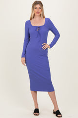 woman wearing a purple ribbed midi dress with a square neckline and drawstring detail, standing and smiling