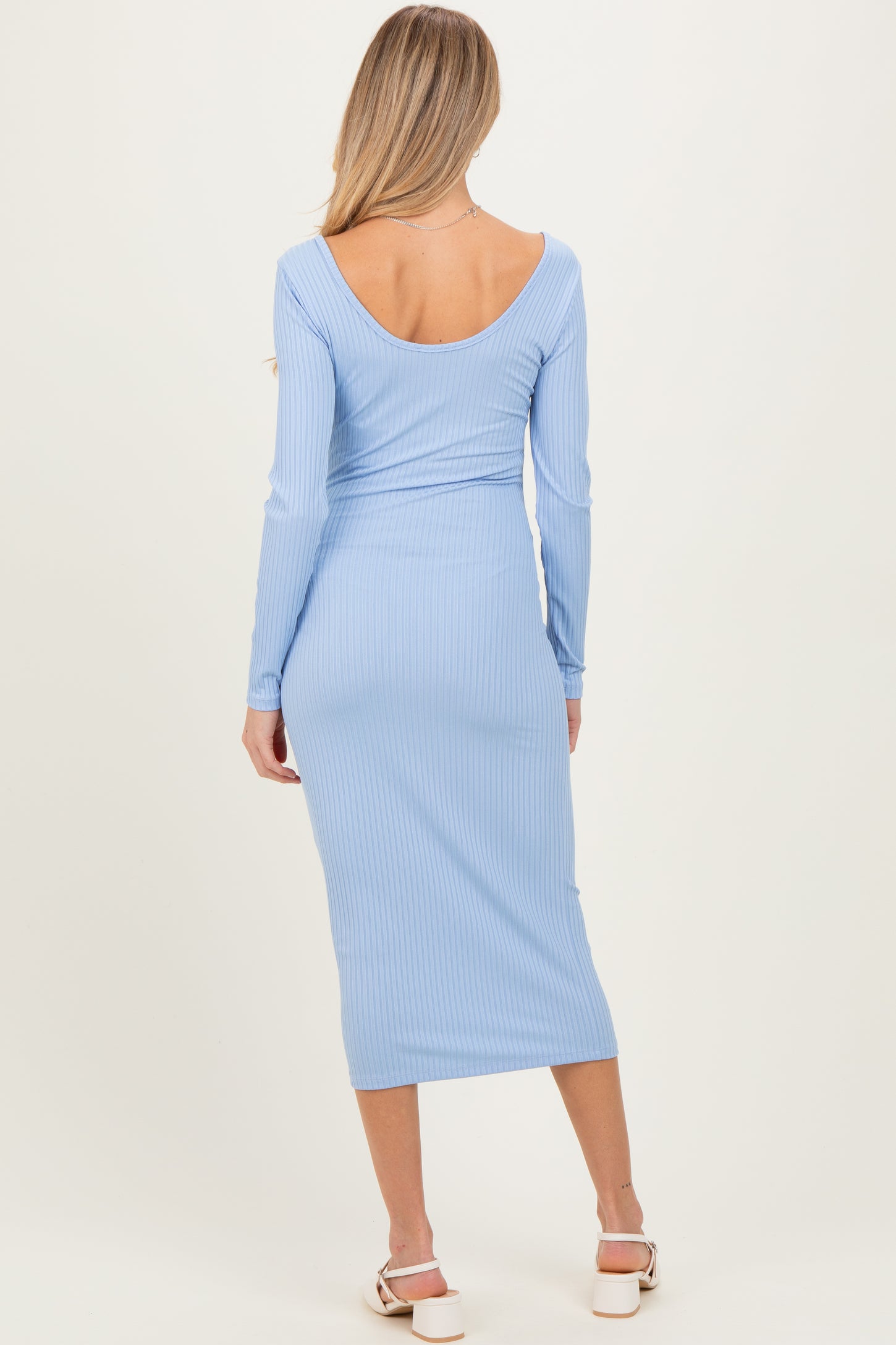 woman wearing a light blue ribbed maternity dress with a fitted silhouette and long sleeves, showing a baby bump