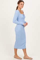 woman wearing a light blue ribbed midi dress with a scoop neckline and buttons, standing sideways