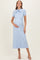 woman wearing a light blue ribbed maternity dress with a bow detail and holding her baby bump