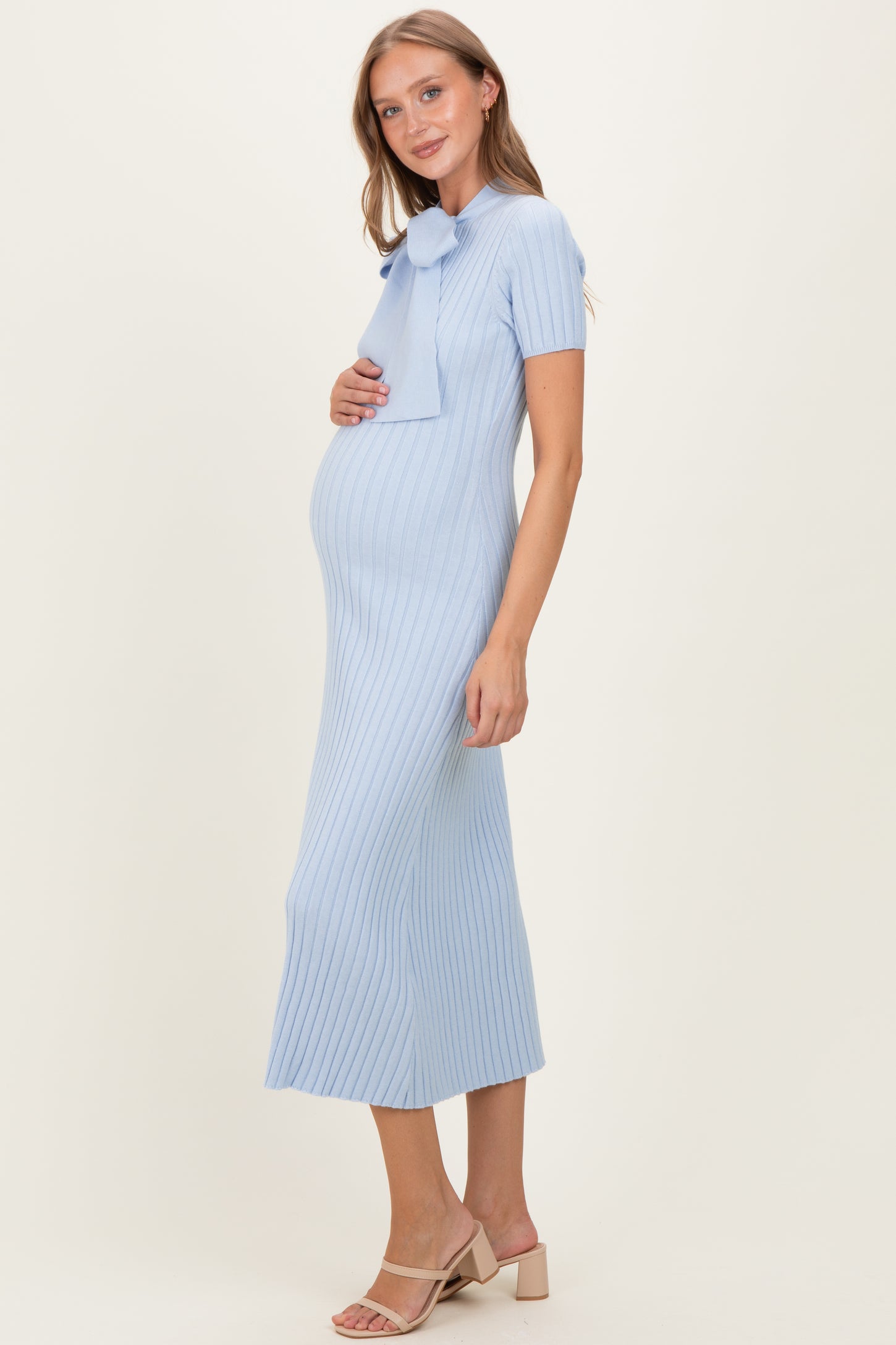 woman wearing a light blue ribbed maternity dress with a bow detail and visible baby bump