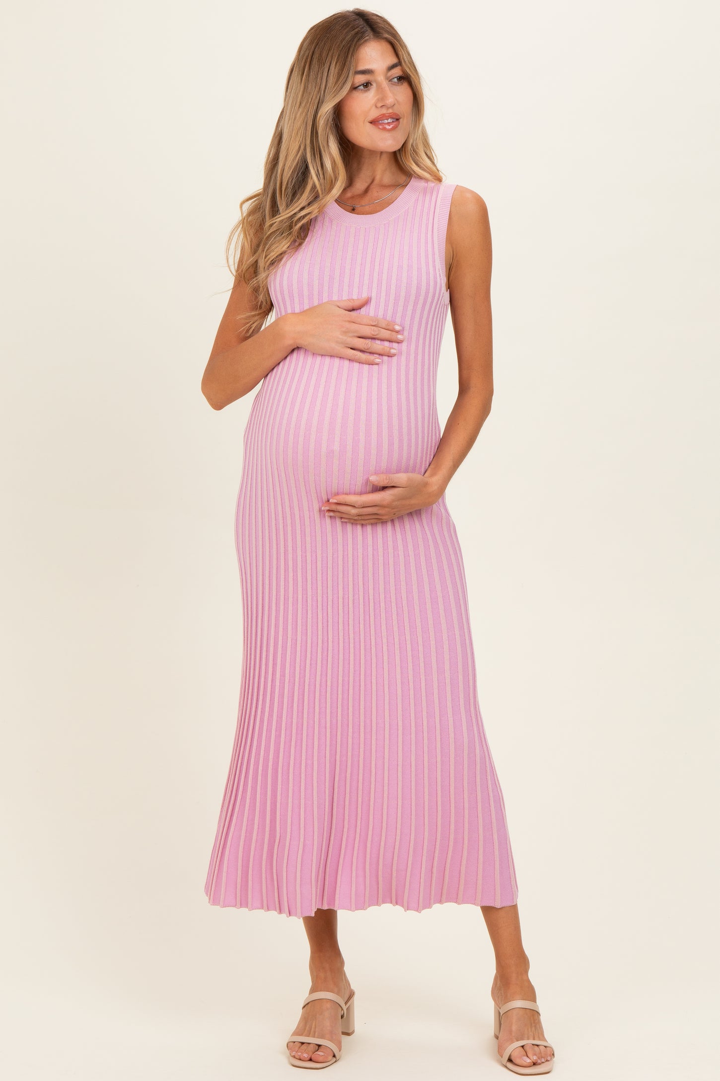 woman wearing a pink ribbed maternity dress and holding her baby bump