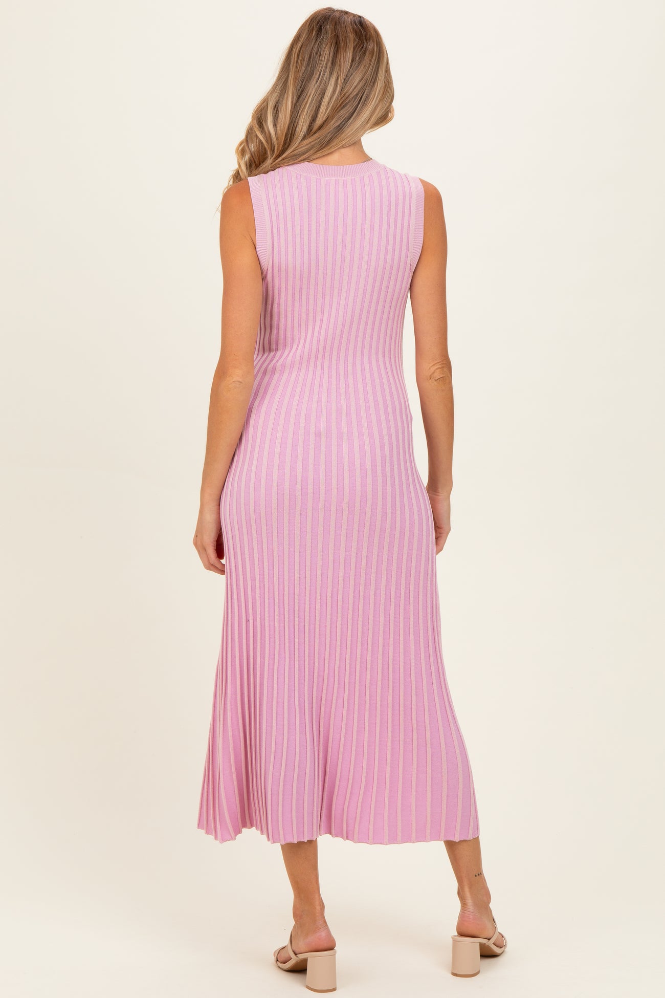 woman wearing a pink ribbed midi maternity dress, showing the back view and featuring a fitted style