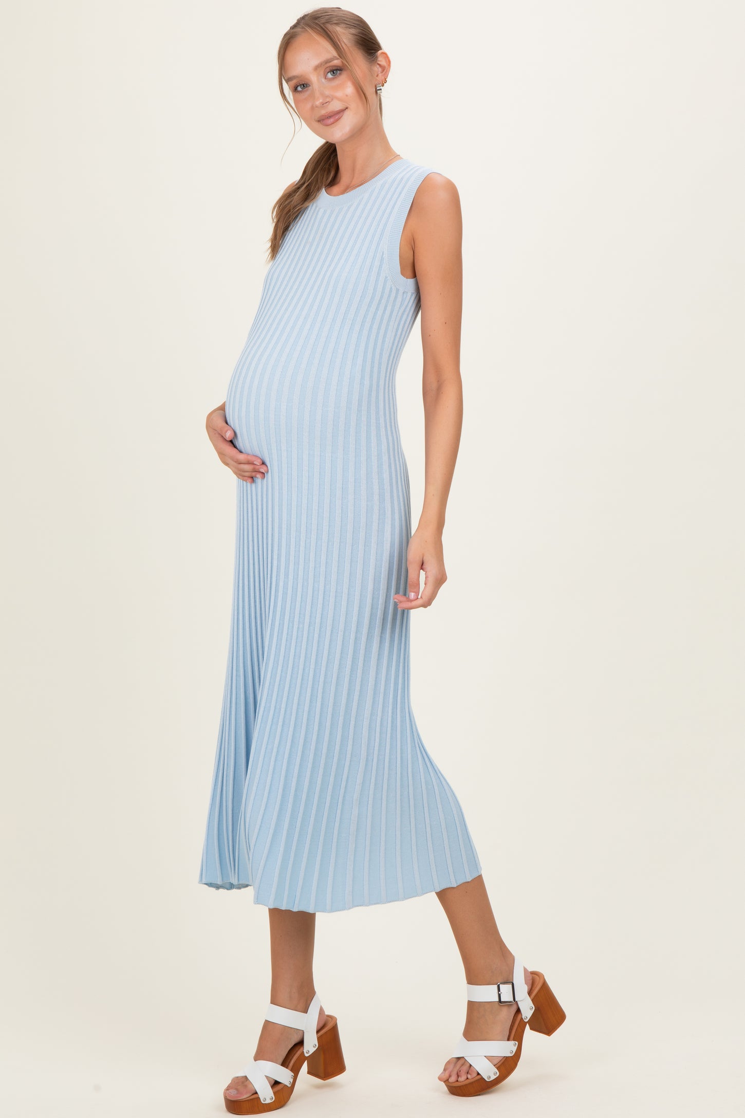 woman wearing a light blue ribbed maternity dress and showing her baby bump
