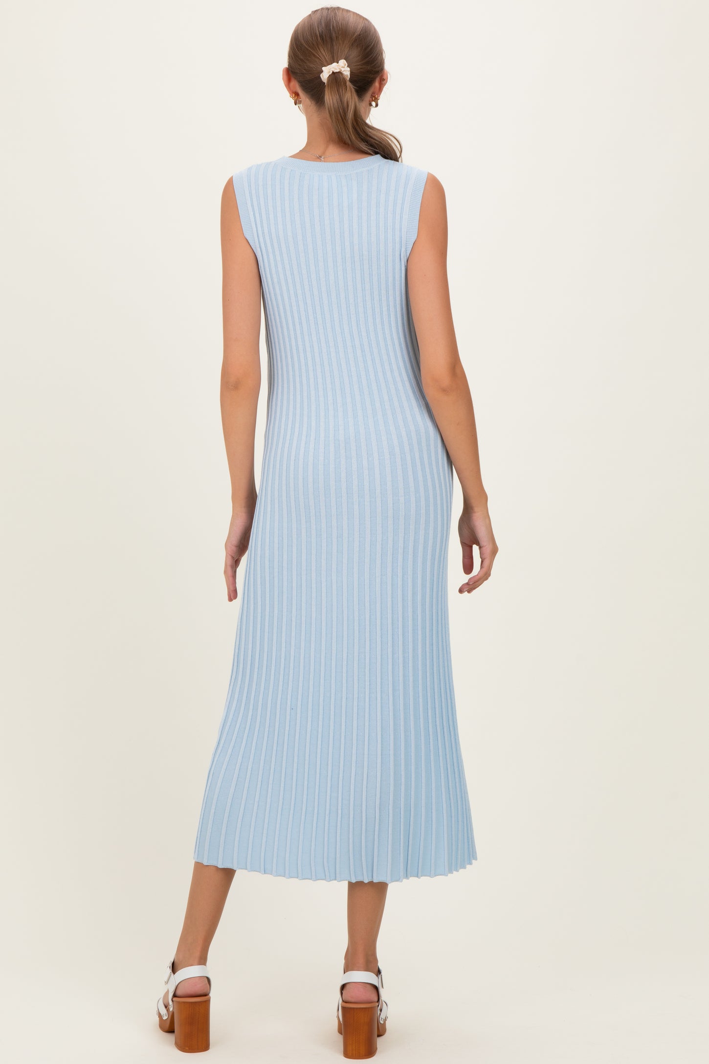 woman wearing a light blue ribbed maternity dress with a midi length and sleeveless design, showing the back view