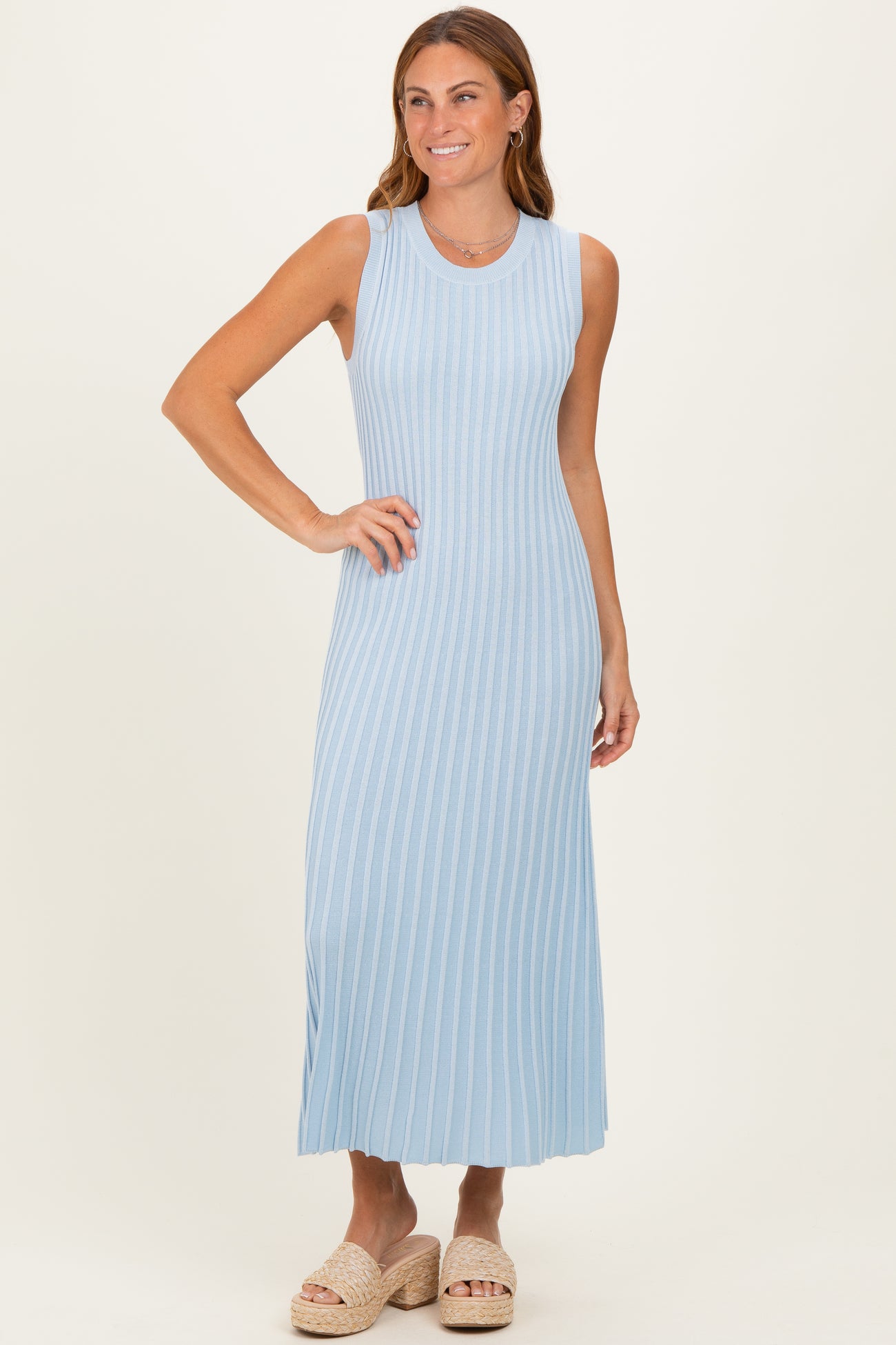 woman wearing a light blue ribbed maxi dress with a sleeveless design and standing in a relaxed pose