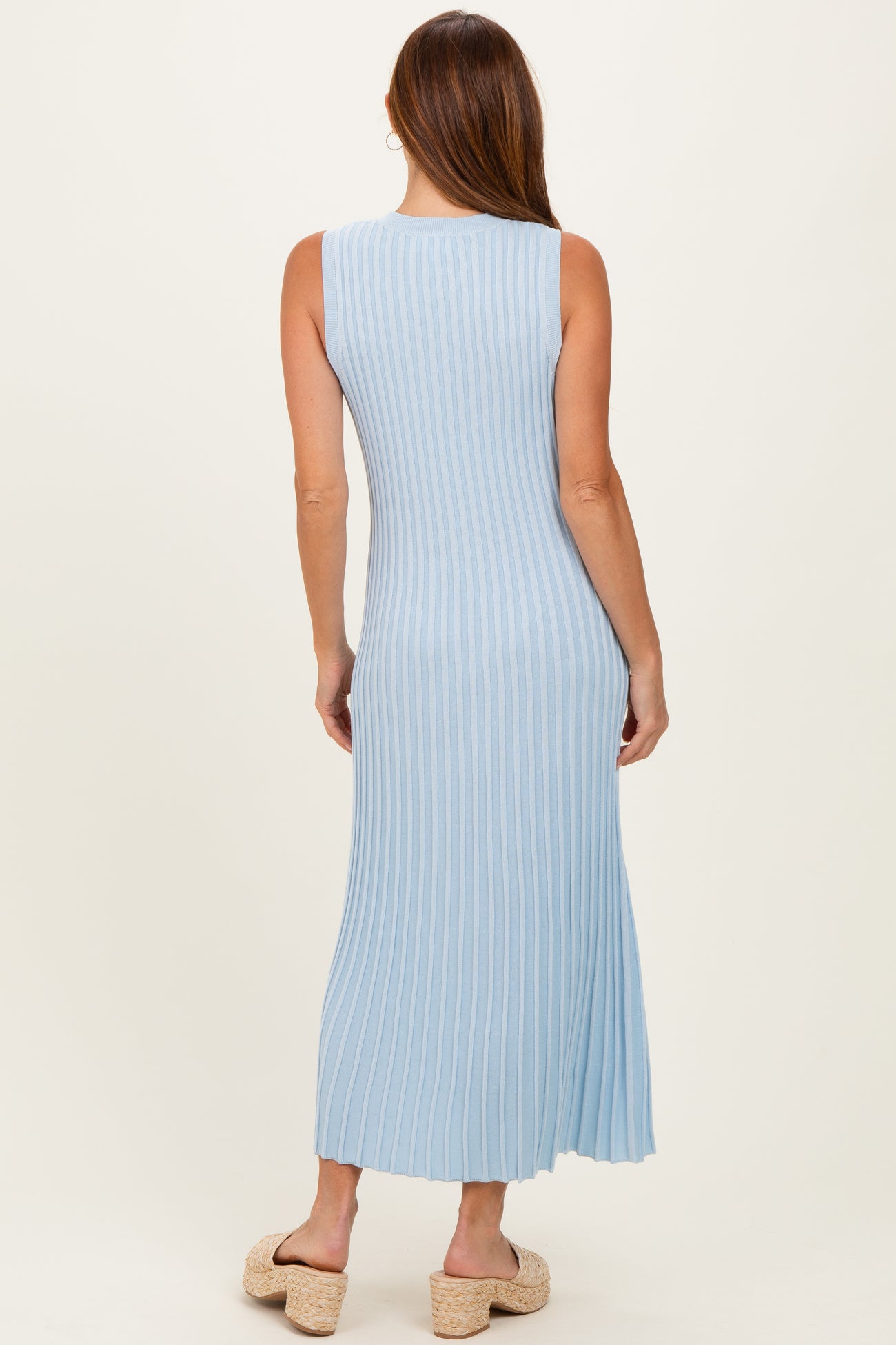 woman wearing a light blue ribbed maxi dress with a fitted silhouette and side slit, seen from the back