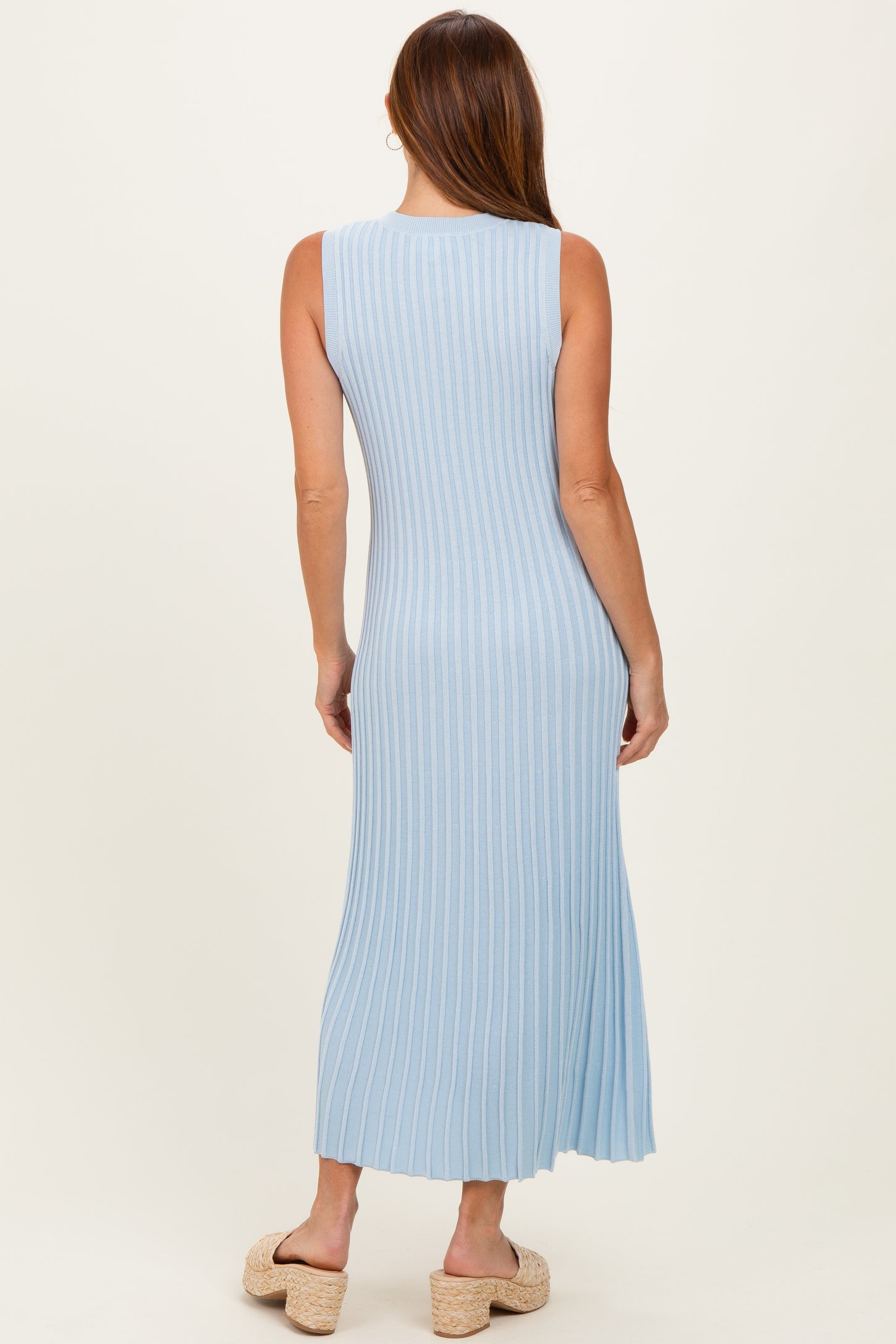 woman wearing a light blue ribbed maxi dress with a fitted silhouette and side slit, seen from the back