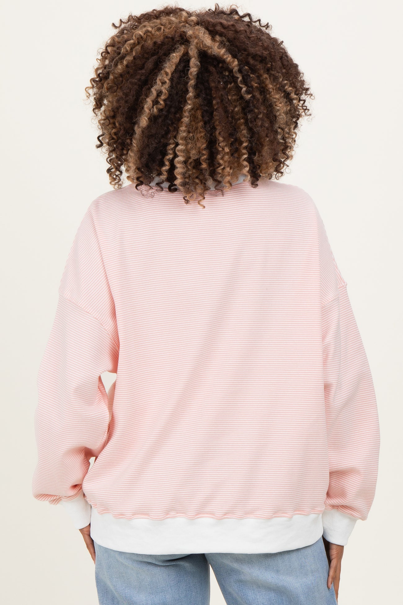 woman wearing a pink striped maternity sweatshirt with balloon sleeves and a white hem, viewed from the back