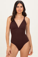 woman wearing a dark brown ribbed one-piece swimsuit with a deep v-neckline and adjustable straps