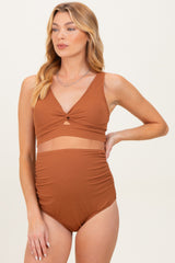 woman wearing a rust-colored maternity bikini top with a twist detail and high-waisted bottom, showing her baby bump