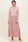 woman wearing a light pink long sleeve ribbed maxi dress with a fitted bodice and flowy skirt, standing against a neutral background