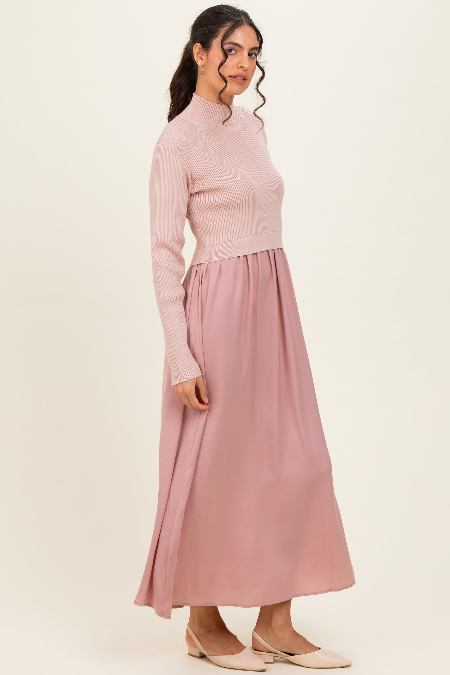 woman wearing a blush pink long sleeve ribbed top and a flowing maxi skirt, styled in an elegant silhouette