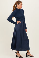 woman wearing a navy blue long sleeve ribbed top with a flowing maxi skirt and black heeled sandals