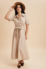woman wearing a beige striped midi shirt dress with a tie waist and short sleeves, styled with a wide-brimmed hat