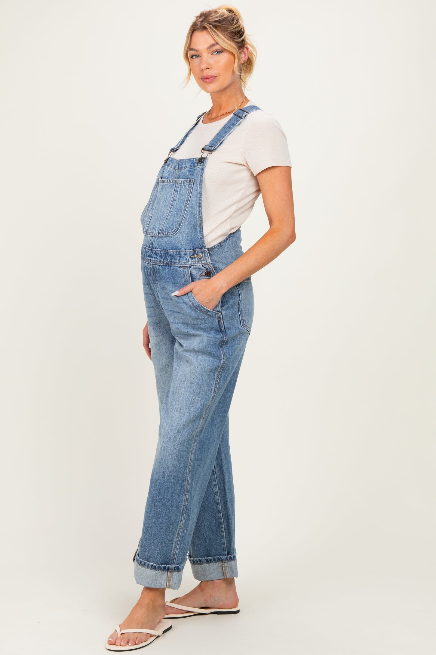 woman wearing a light blue maternity overall with rolled cuffs and a fitted t-shirt, showcasing a baby bump