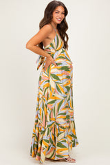 woman wearing a colorful floral maternity maxi dress with a tiered skirt and a visible baby bump