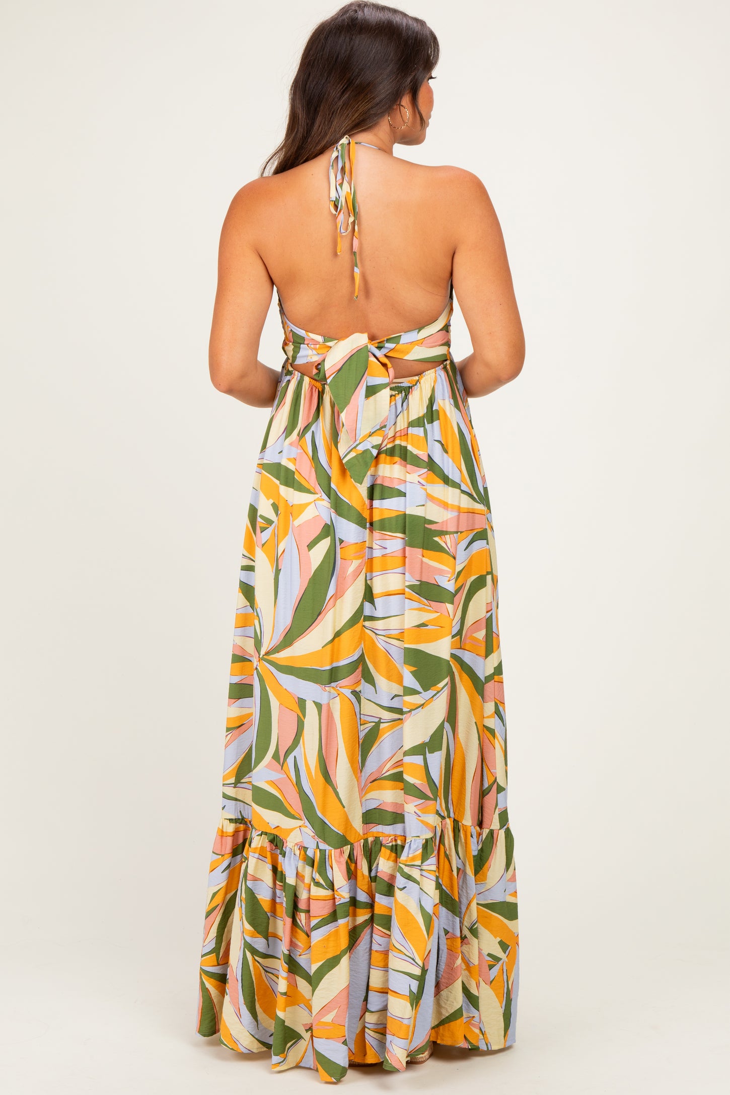 woman wearing a colorful floral print maternity maxi dress with a halter neck and back tie detail