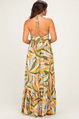 woman wearing a colorful floral print maternity maxi dress with a halter neck and back tie detail