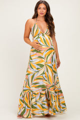 woman wearing a colorful floral print maternity maxi dress with a flared hem and holding her baby bump