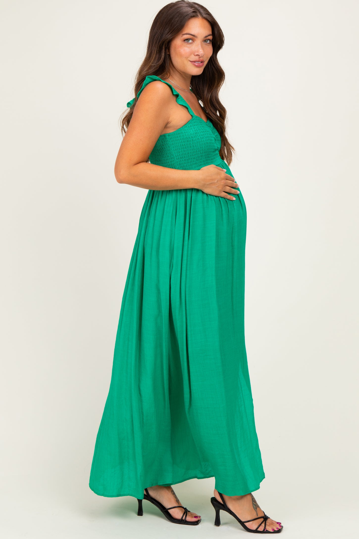 woman wearing a green maternity maxi dress with ruffled straps and a baby bump visible