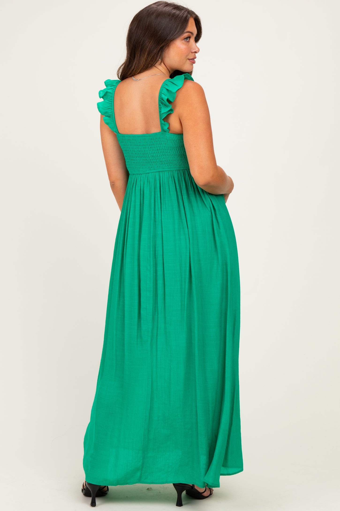 woman wearing a green maternity maxi dress with ruffled straps and smocked bodice, showing a baby bump