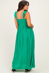 woman wearing a green maternity maxi dress with ruffled straps and smocked bodice, showing a baby bump
