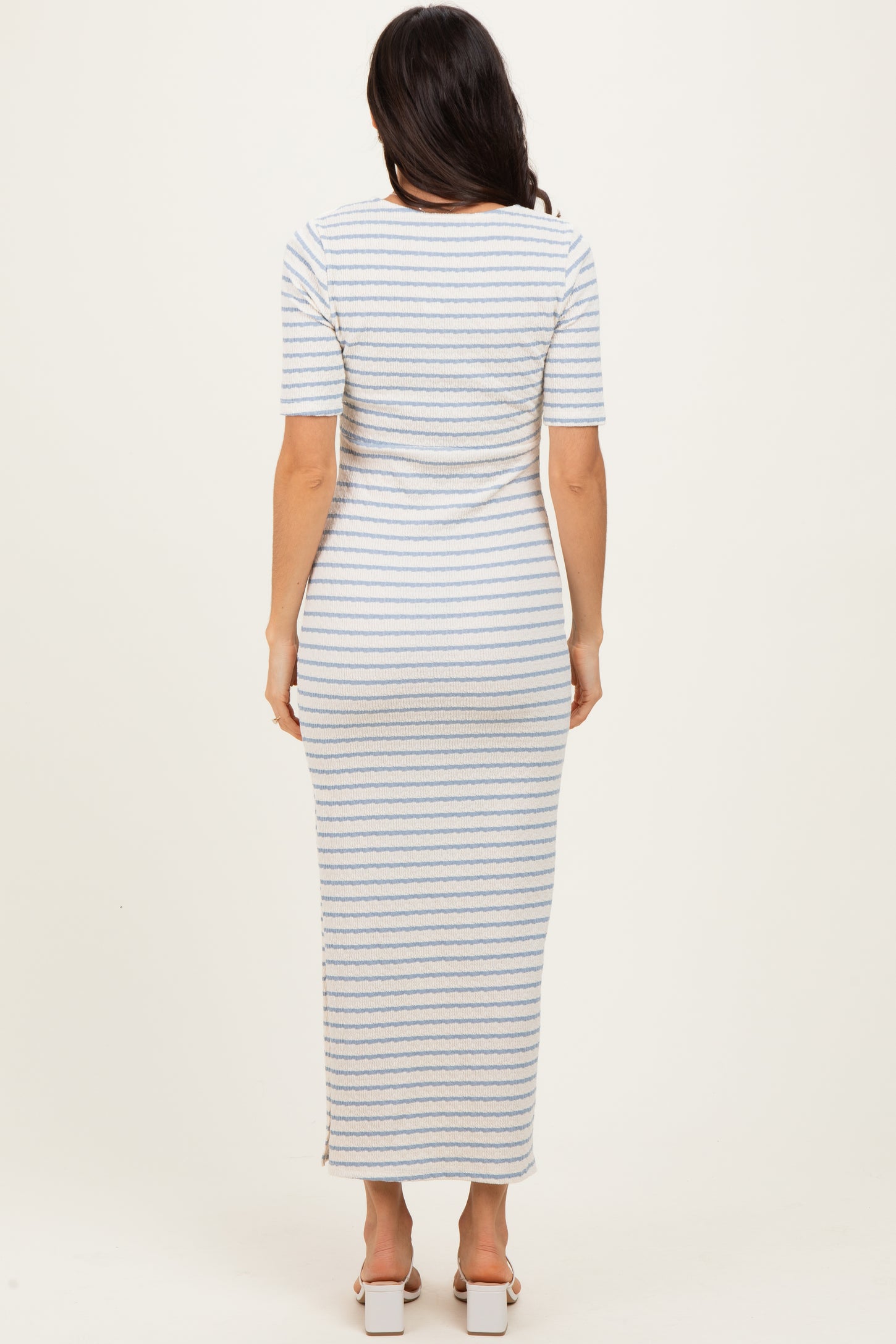 woman wearing a fitted maxi dress with horizontal blue and white stripes and short sleeves, viewed from the back